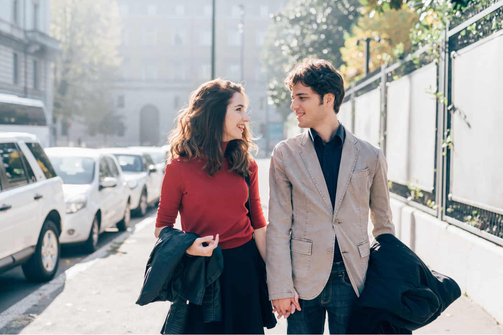 young couple holding hands while walking the street