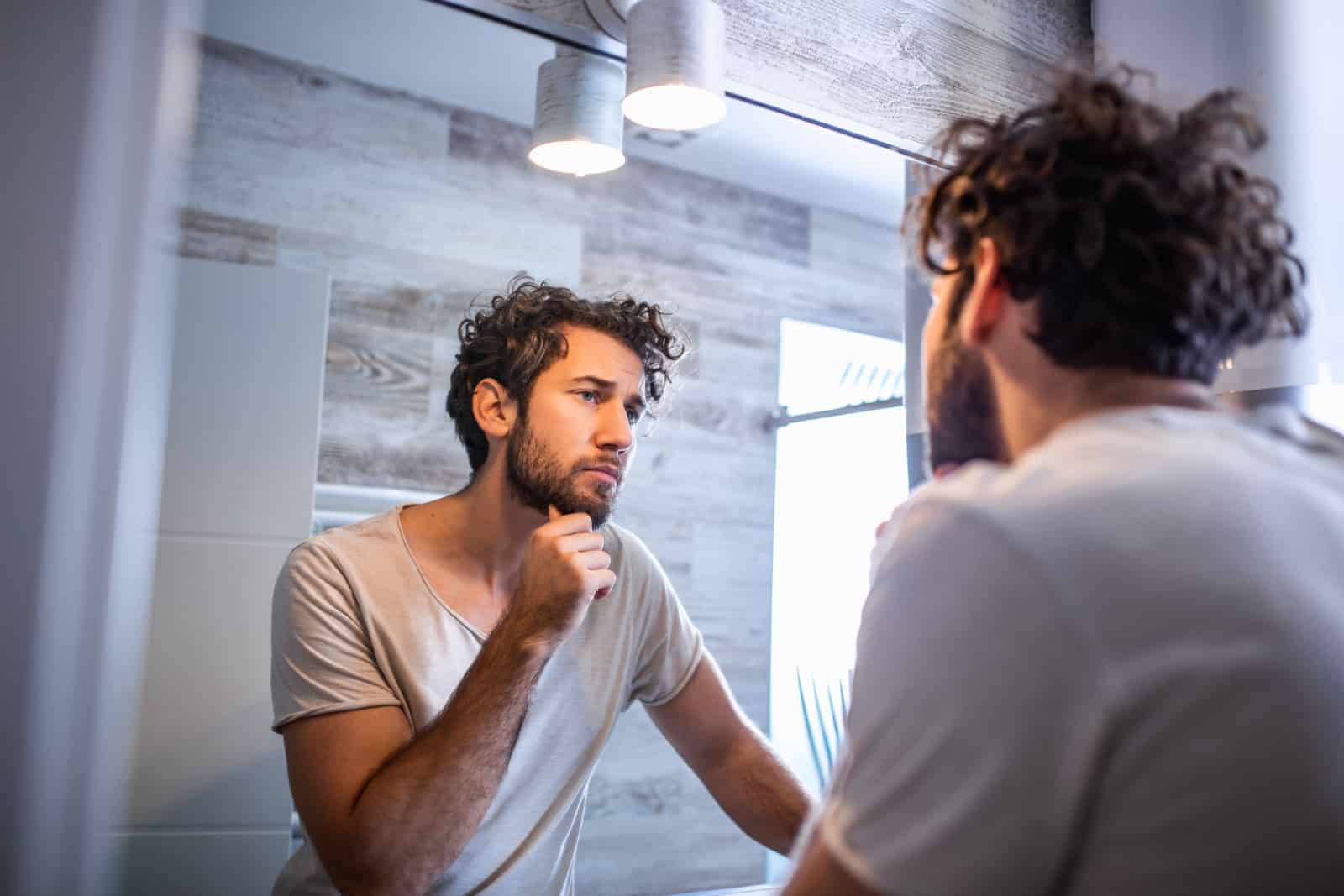 Handsome man in the bathroom looking in mirror.