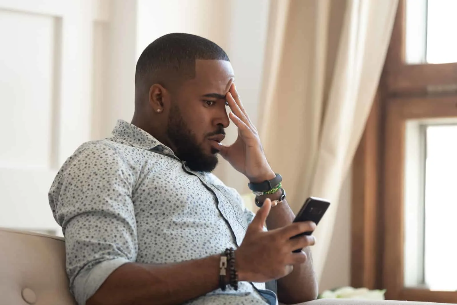 Disappointed african American millennial male looks at phone