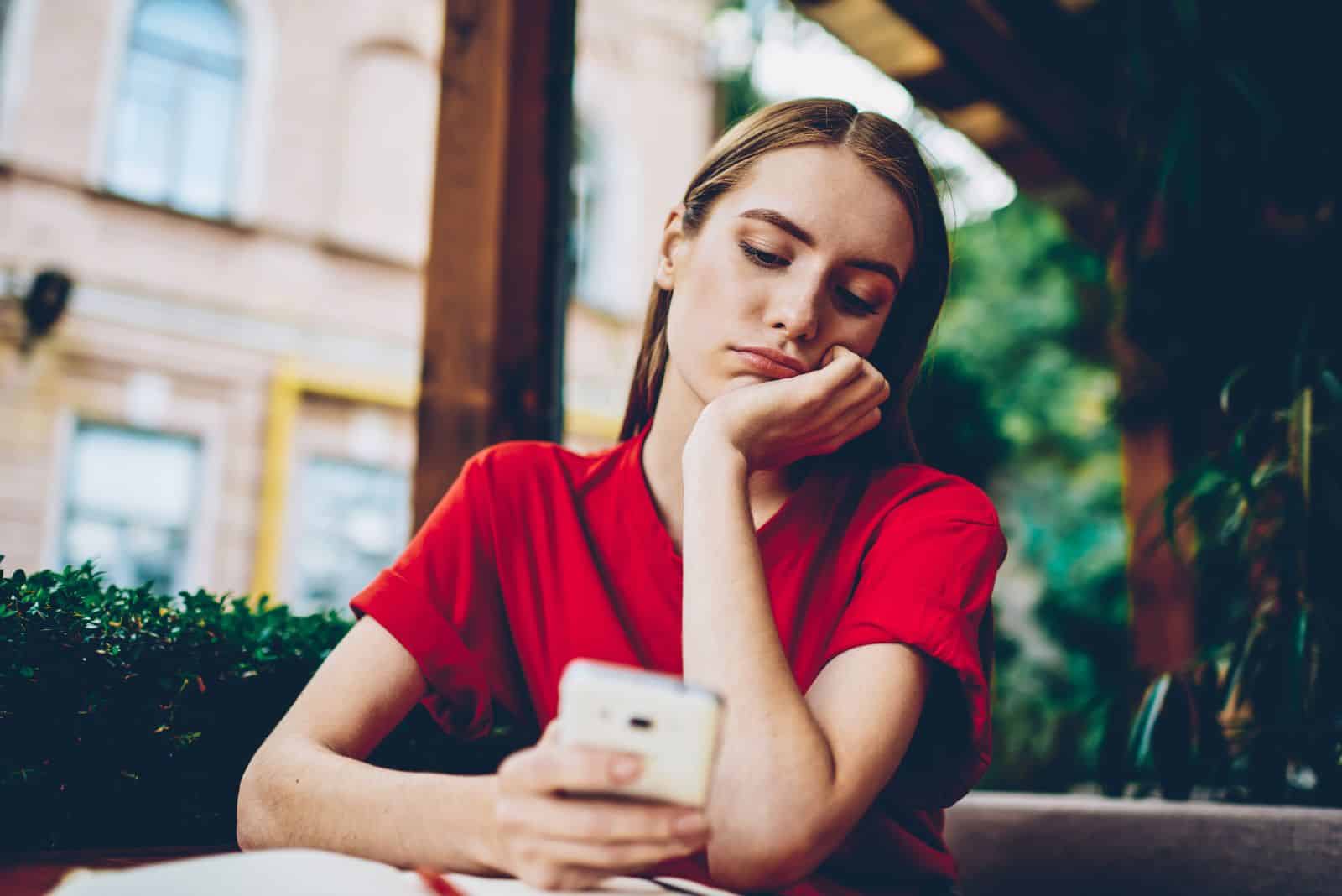 a thoughtful girl is sitting with a phone in her hand