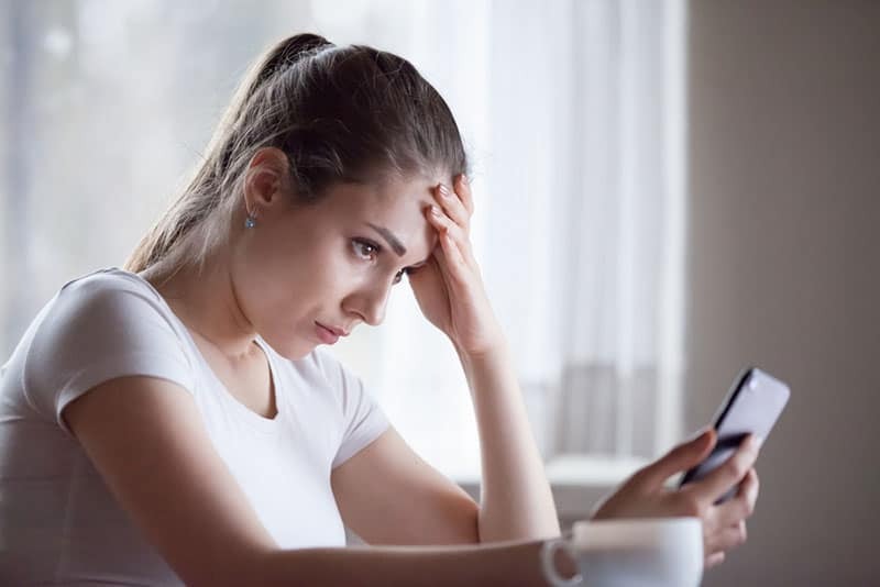 worried woman looking at mobile phone