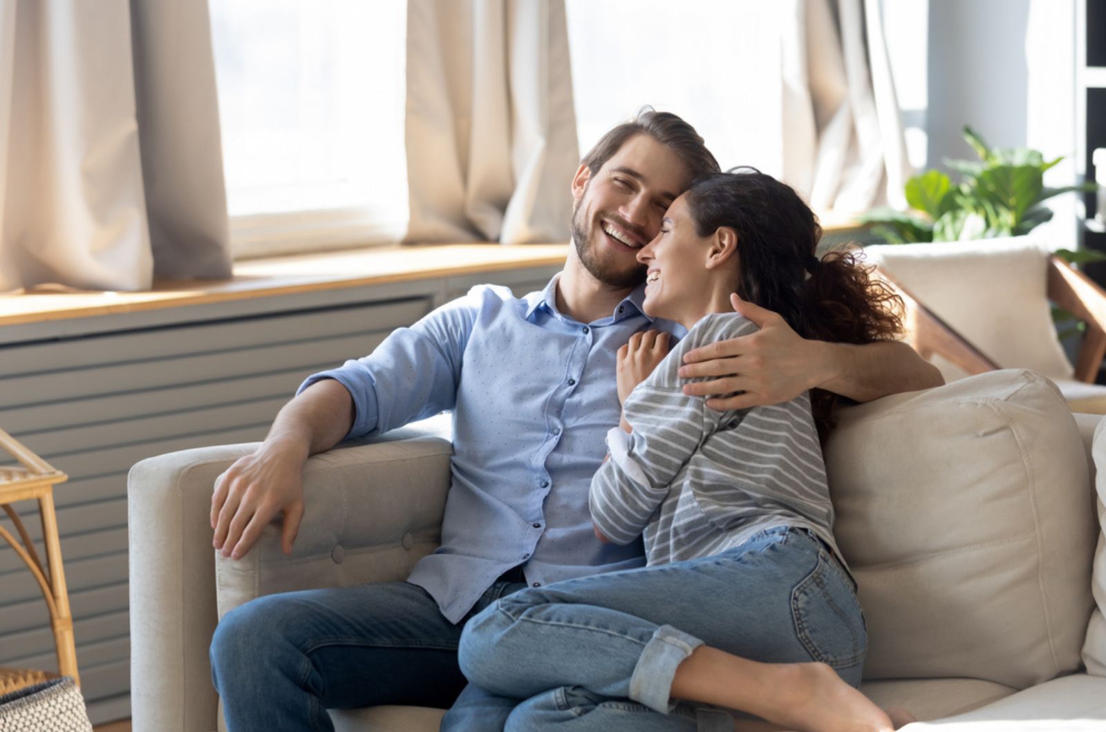 casal a sorrir e a abraçar-se no sofá