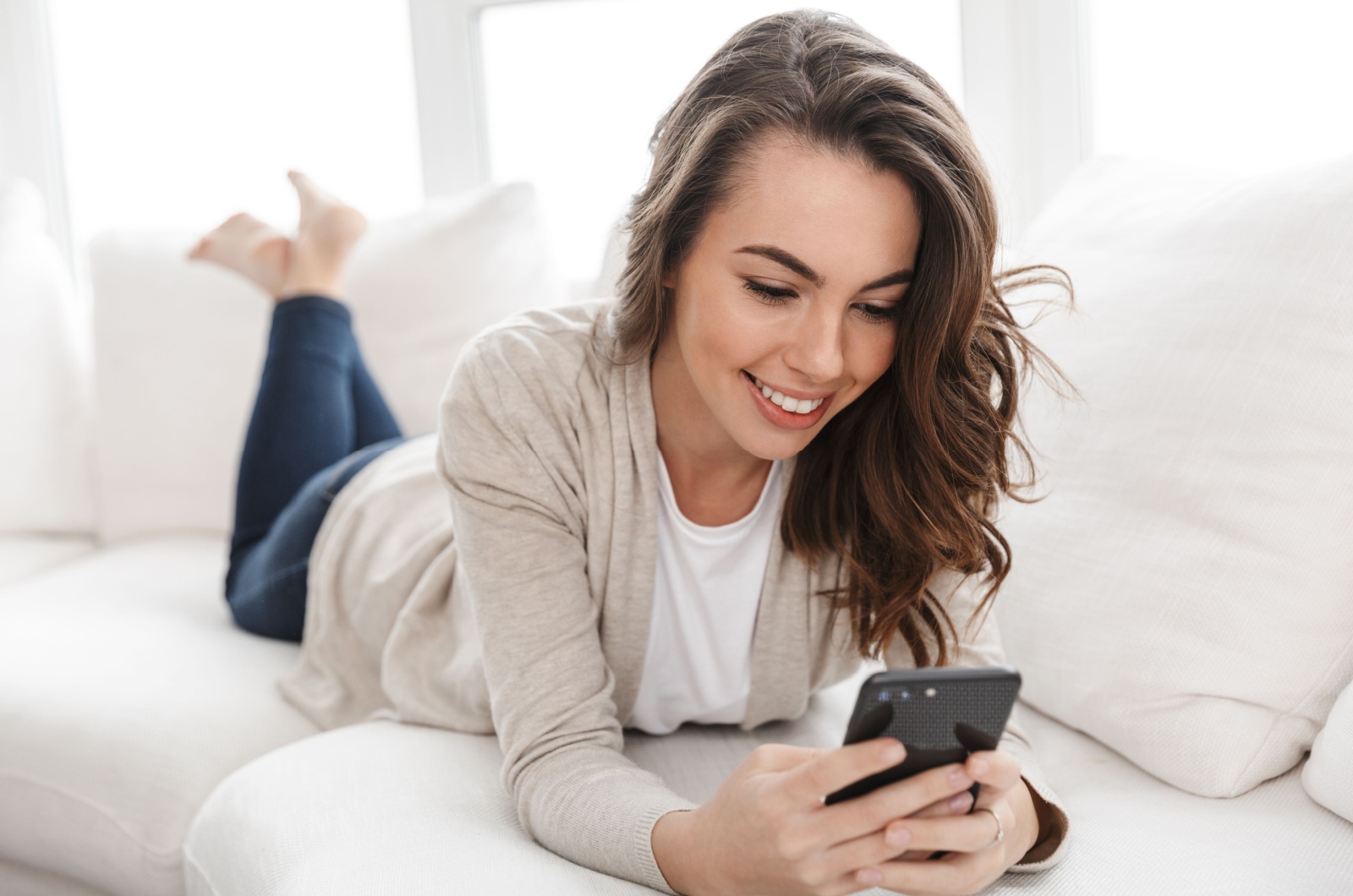 mujer tumbada en el sofá enviando mensajes de texto