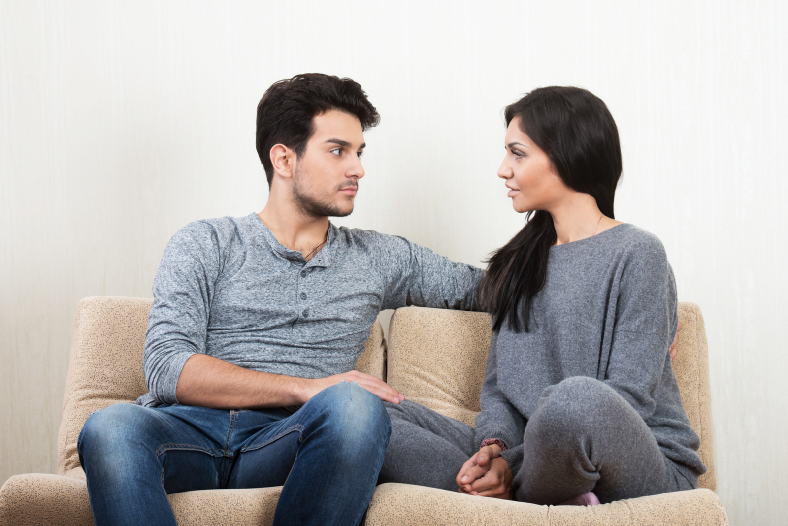 Jovem casal feliz a conversar sentado num sofá