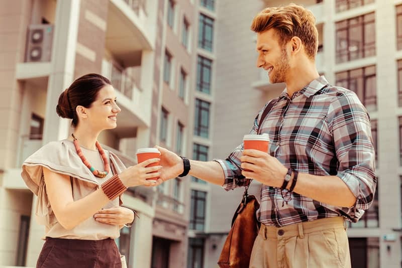 a man gives coffee to a smiling woman