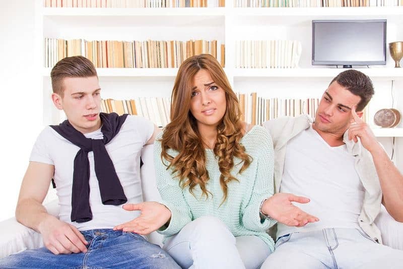 confused woman sitting between two men