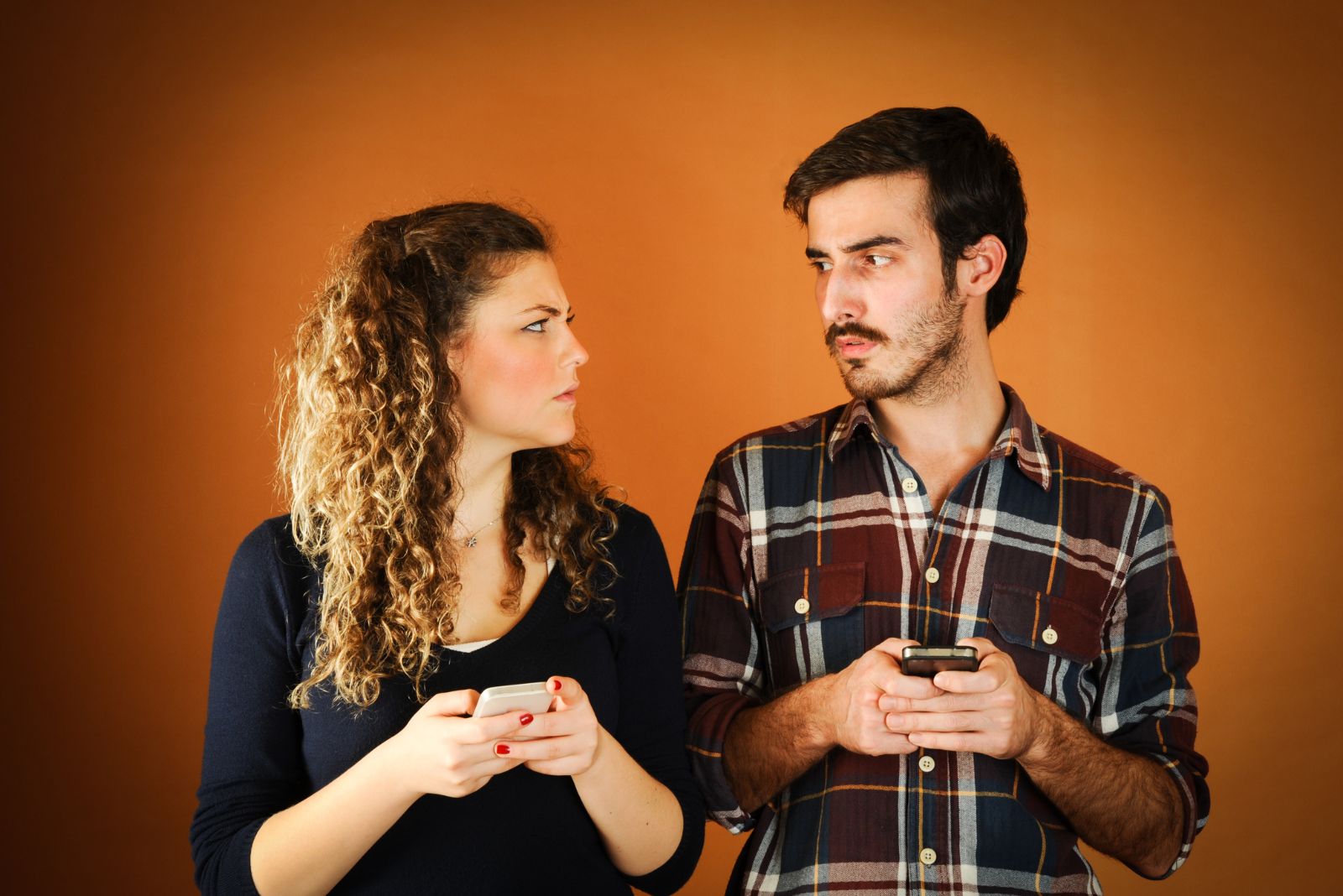 man and woman holding phones and looking at each other