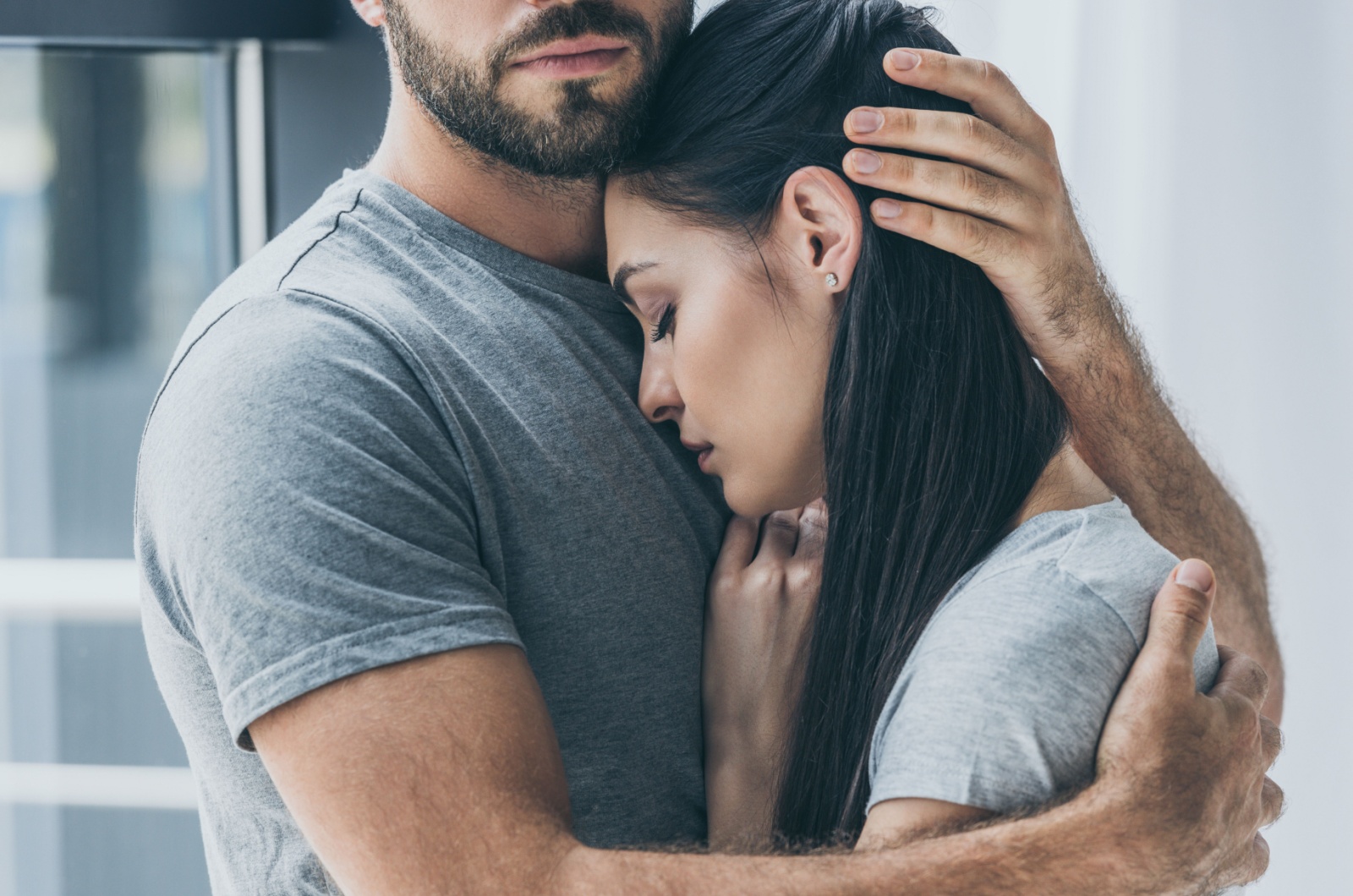 man hugging and supporting young sad woman