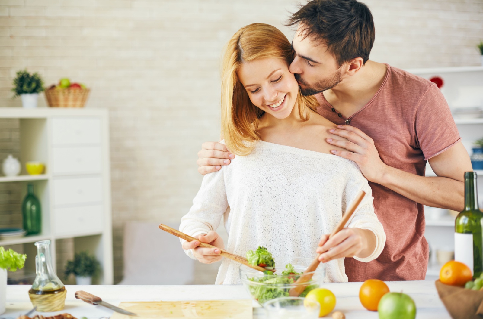 man kissing his wife while she cooking