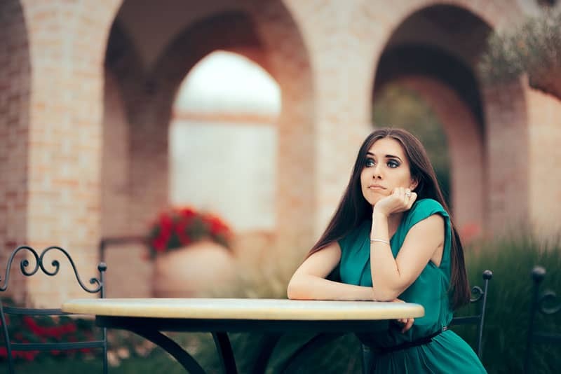 mujer triste sentada sola junto a la mesa