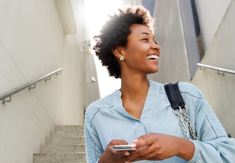 mujer sonriente con el teléfono en la mano