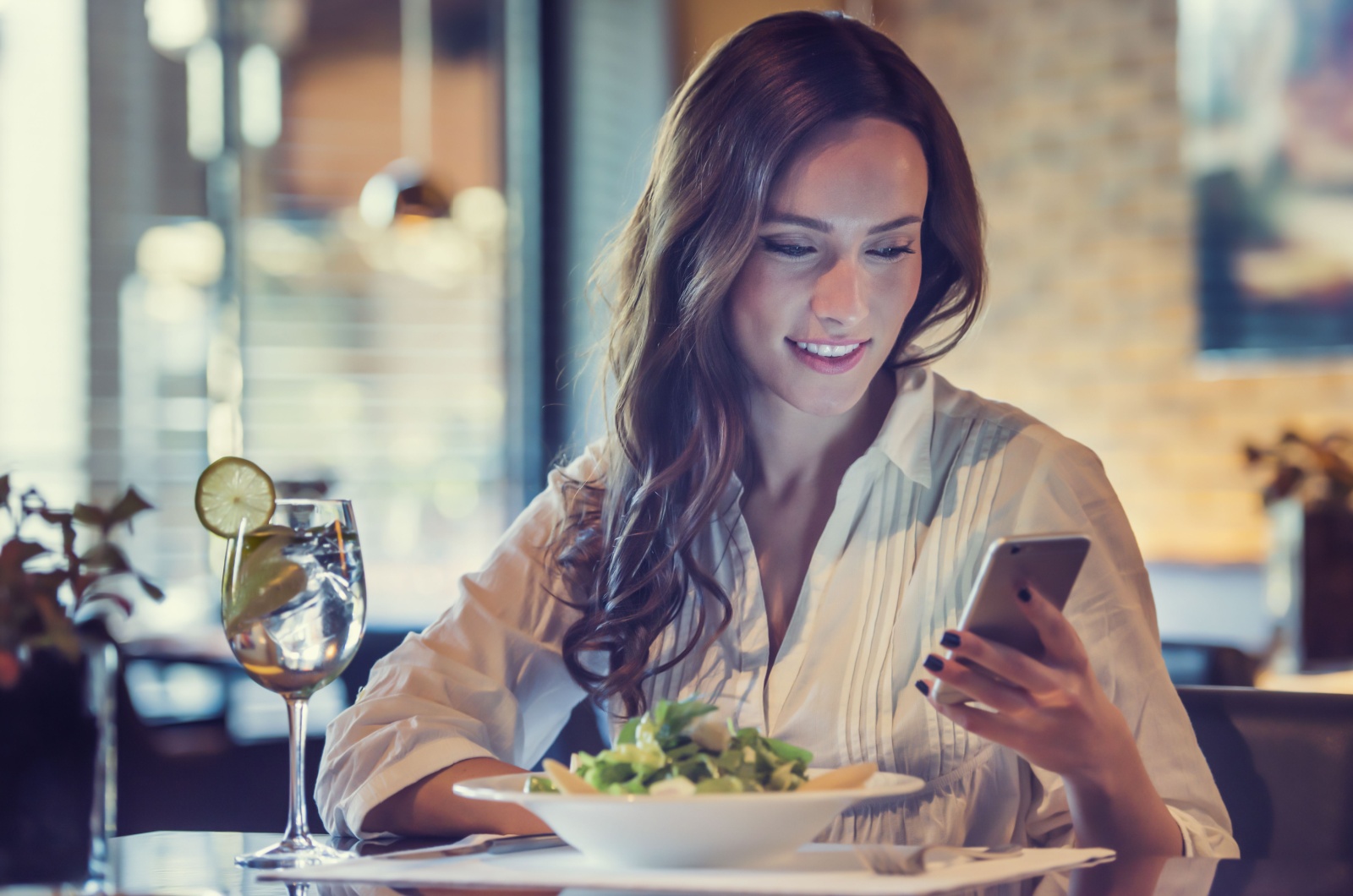 mulher a almoçar e a utilizar o telemóvel