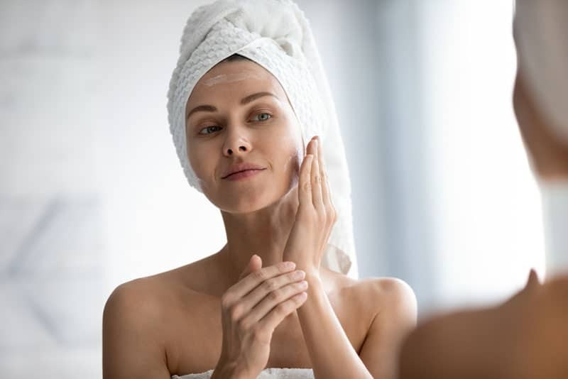 woman putting moisture creme on face