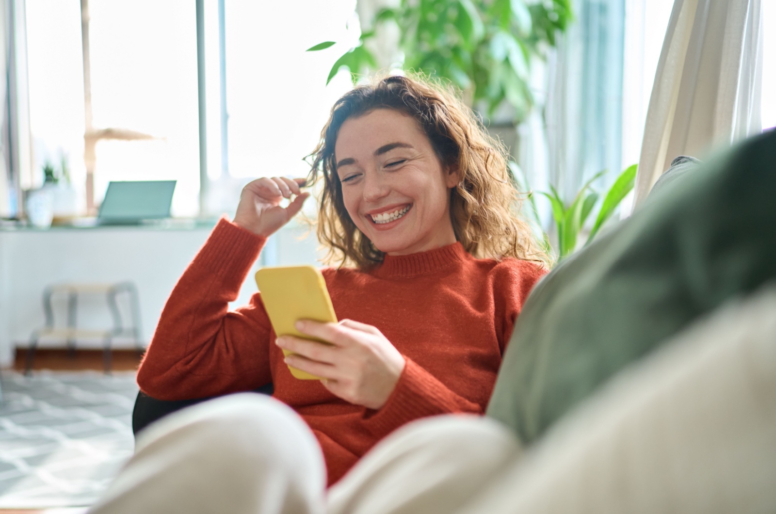 mujer sentada en el sofá usando el teléfono móvil