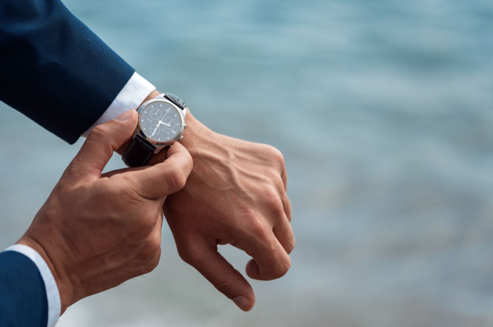 A man in a business suit checking a wrist watch on his hand