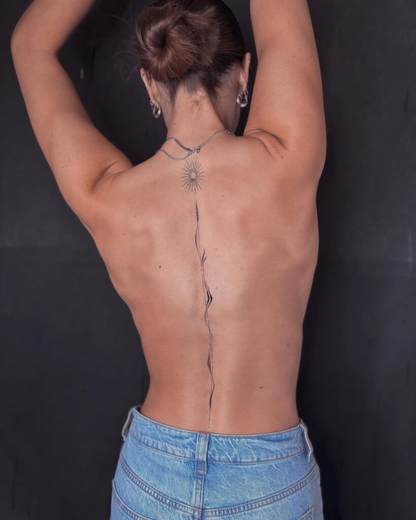 Tatuaggio della colonna vertebrale in codice morse travestito da ghirigori astratti