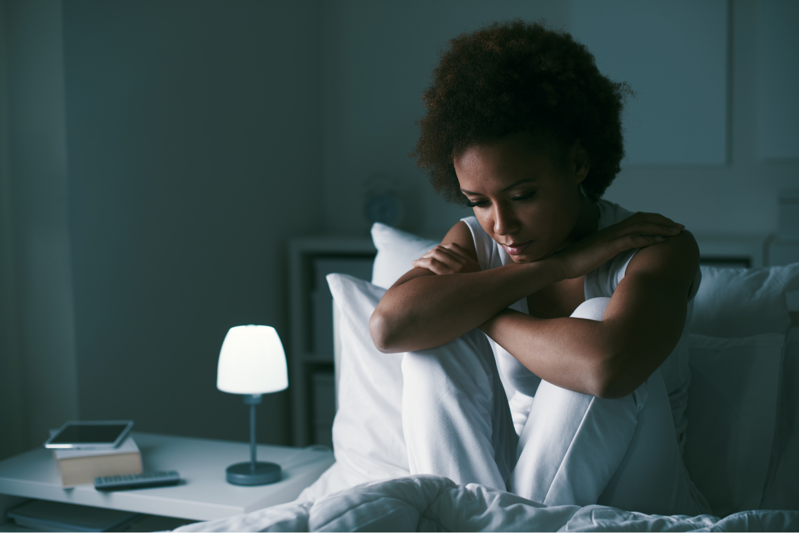 Sad depressed woman sitting in her bed late at night