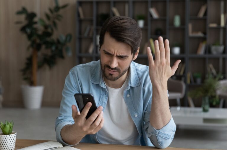 hombre disgustado mirando un teléfono