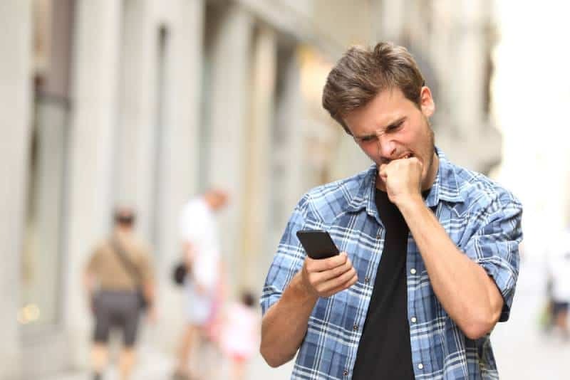 uomo arrabbiato che guarda il telefono