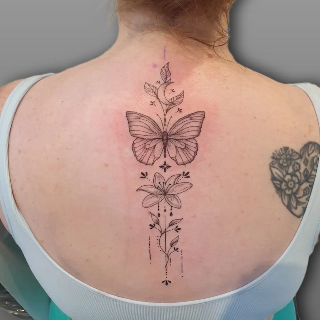 tatuagem de borboleta lírio flor na coluna vertebral