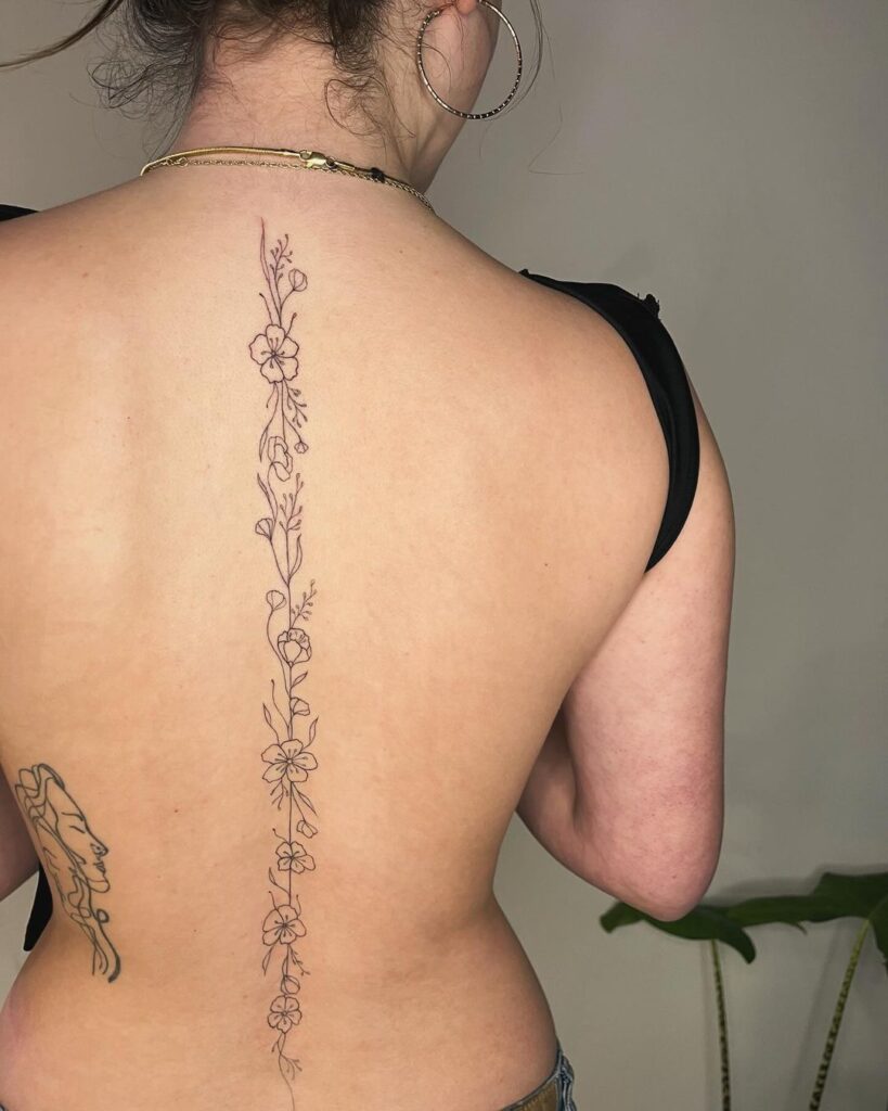 floral spine tattoo on a single straight line