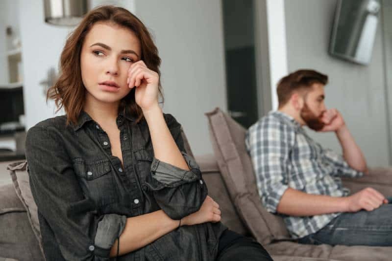 mujer triste llorando y sentada con un hombre en el sofá