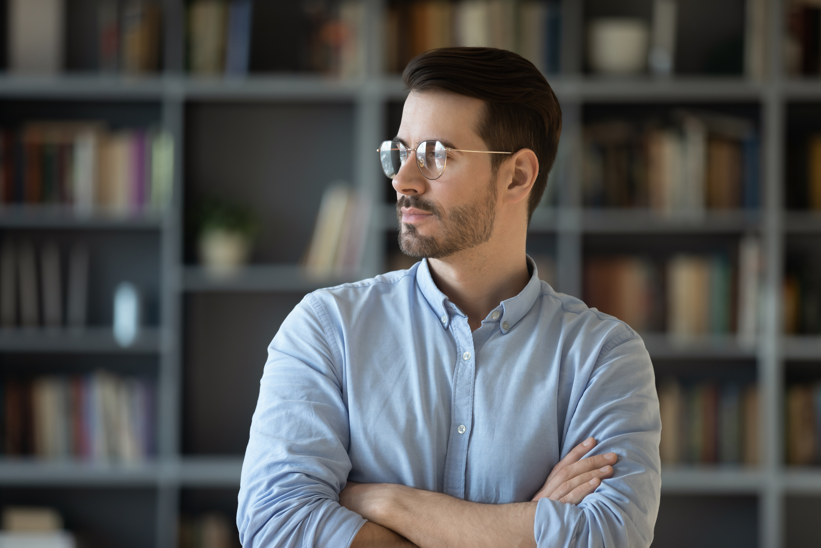 hombre serio con gafas de pie y mirando a lo lejos