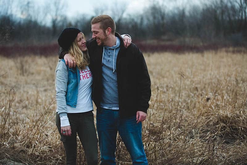 pareja sonriente abrazándose en el campo