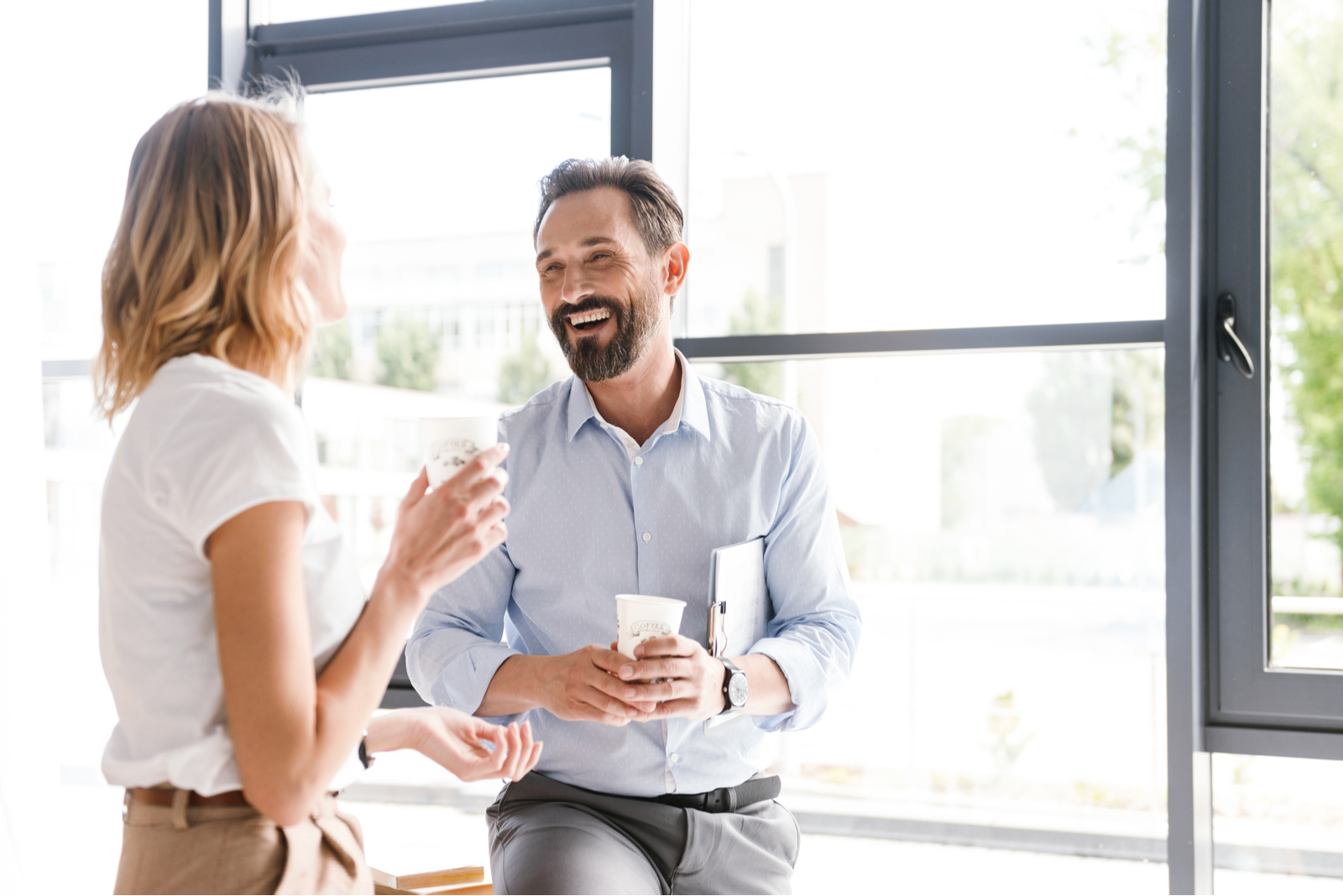 homem sorridente a falar com uma mulher no escritório