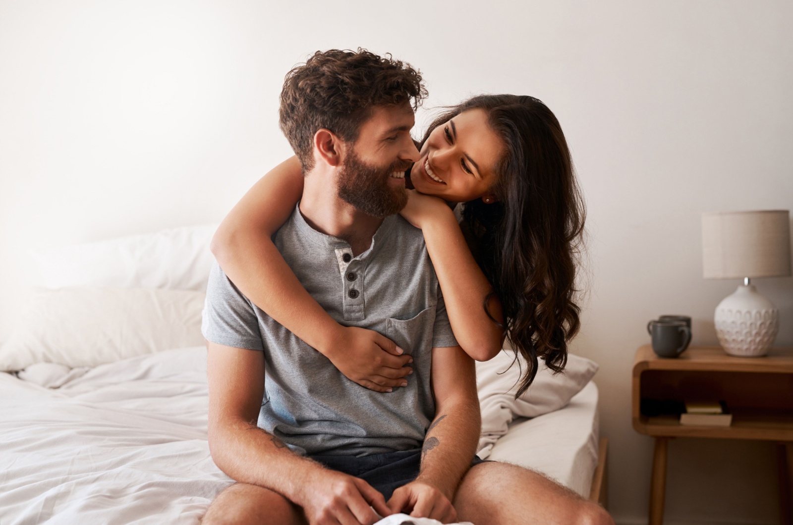 woman hugging man while sitting on bed