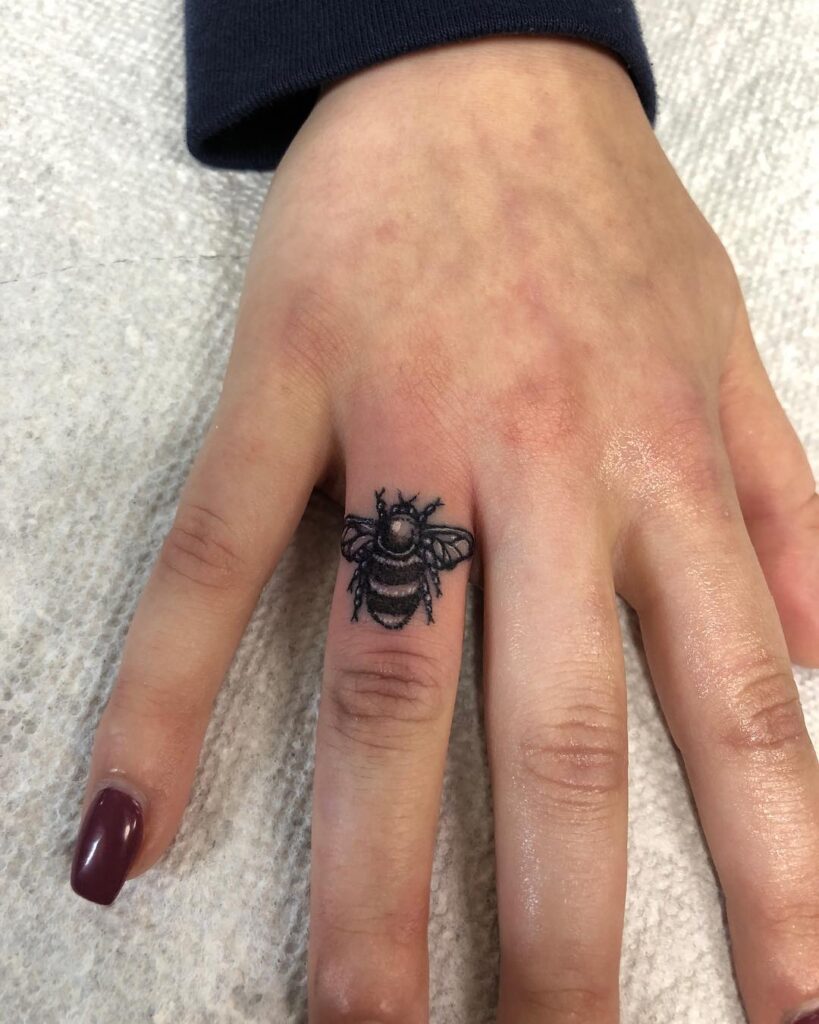 Tatuaje de abeja en el dedo