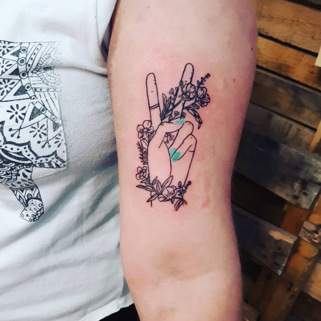 Tatuagem hippie com sinal V de criança florida