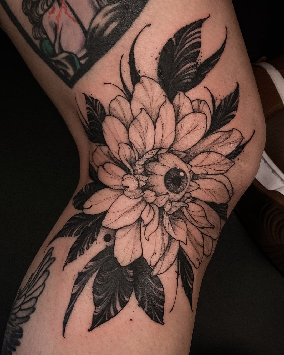 tatuagem de olho com flores e folhas a preto