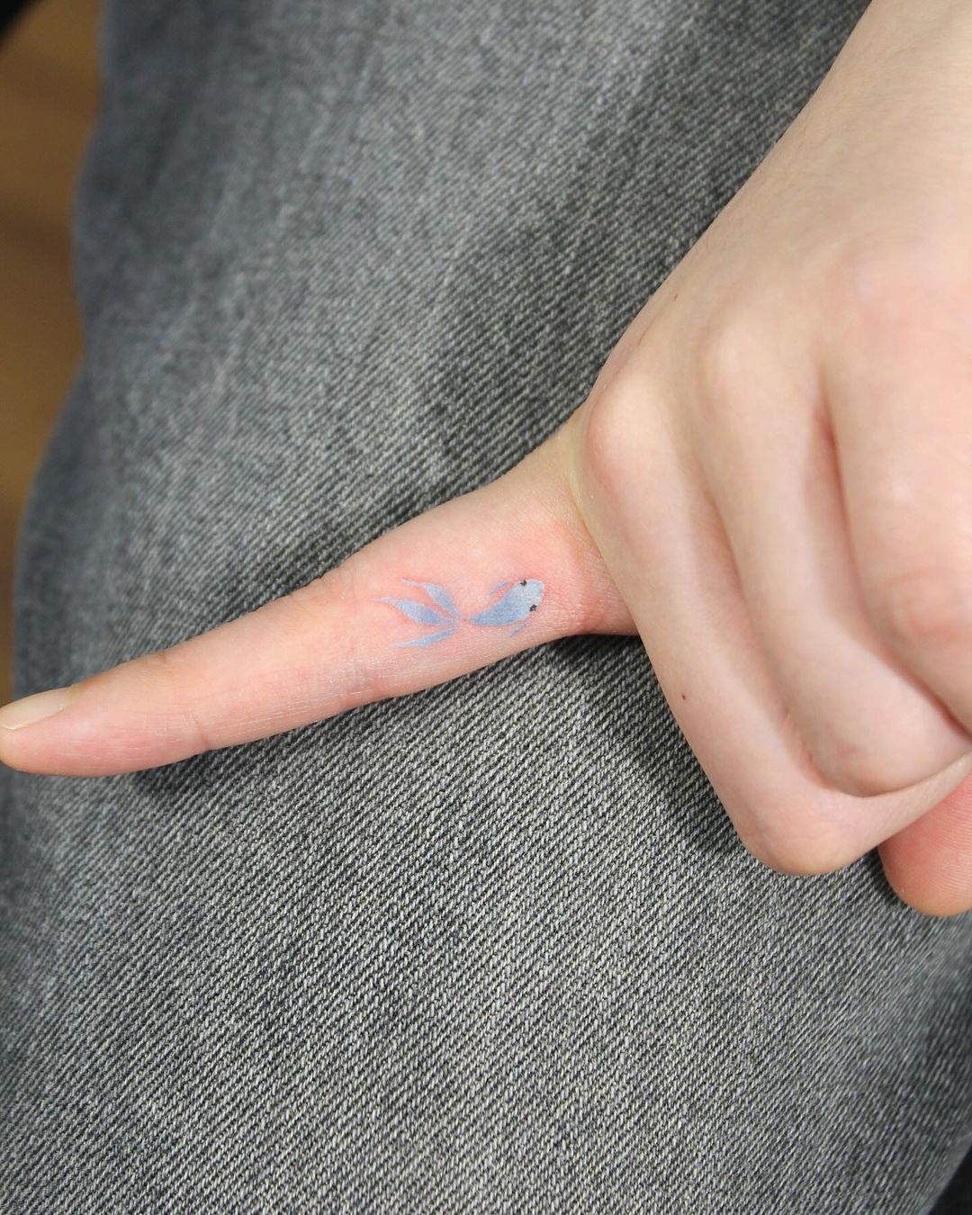mini tatuaje de pez en el dedo