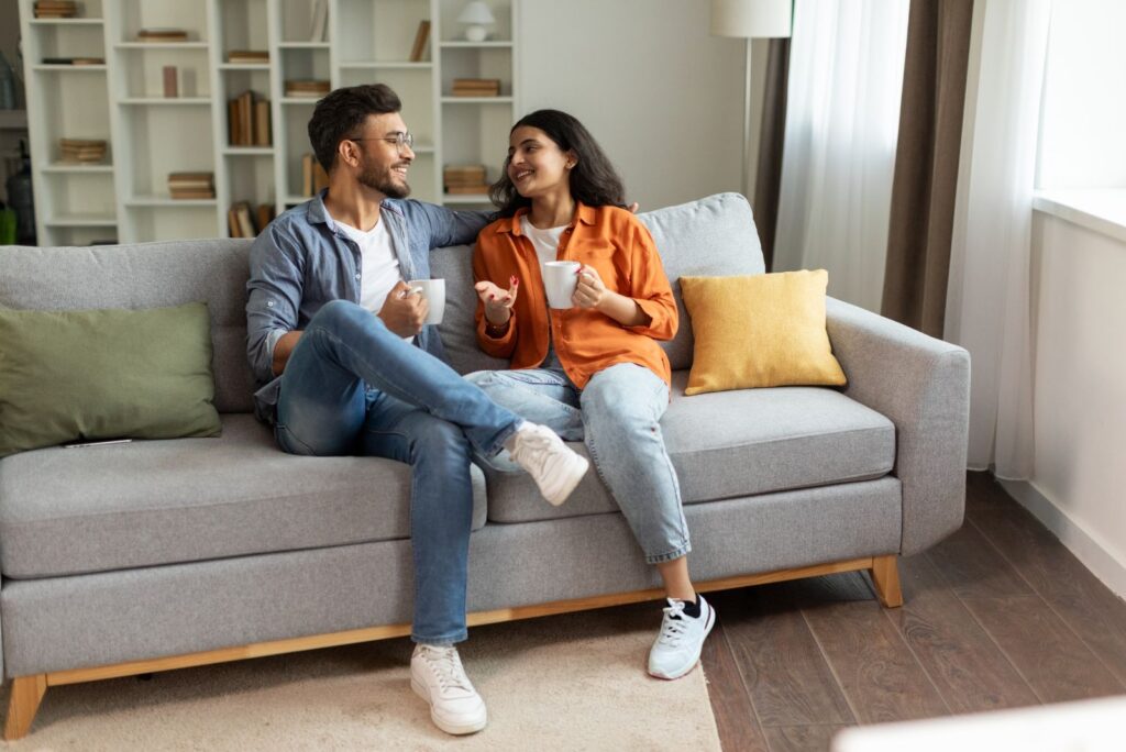 smiling man and woman sitting on couch and talking