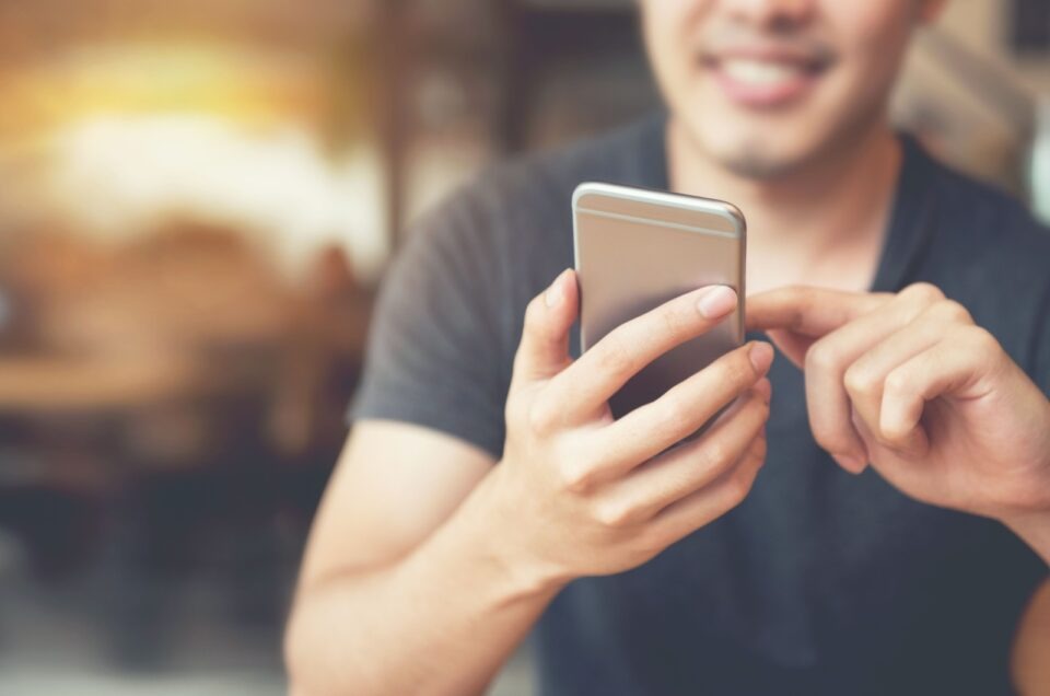 homem sorridente com o telemóvel na mão