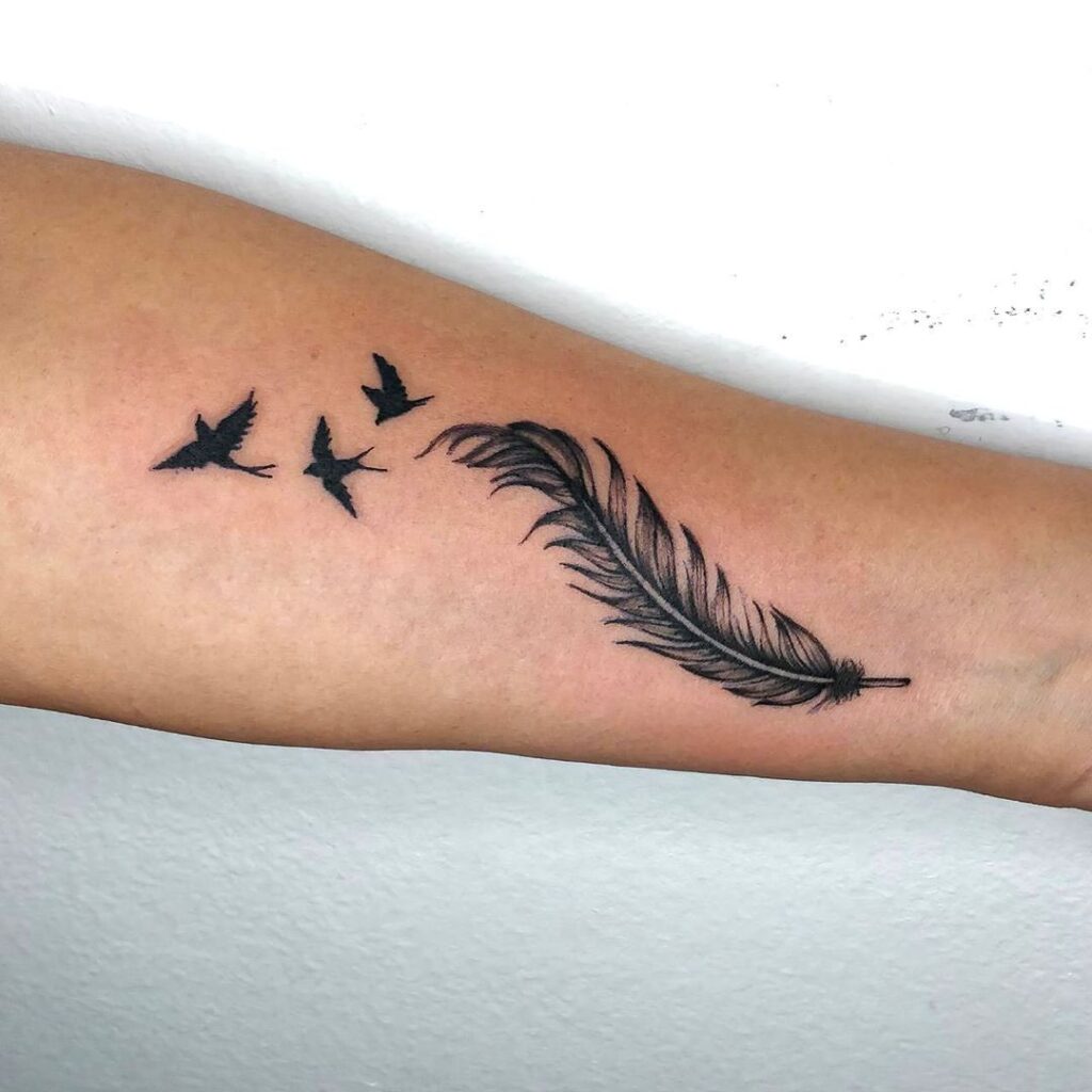 Tatuagem de antebraço com penas e andorinhas