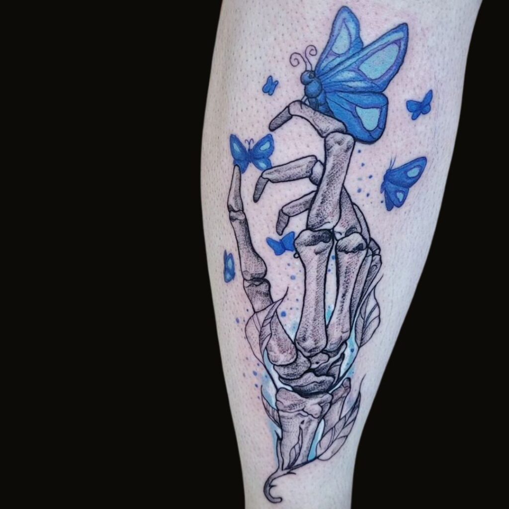 Tatuaggio con mano scheletrica e farfalle