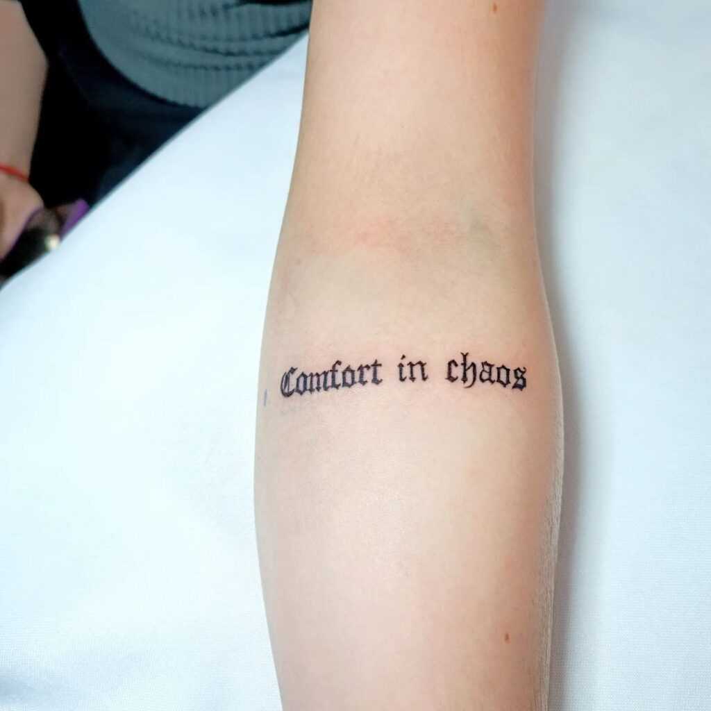 Tatuaggio con scritte sull'avambraccio "Comfort in Chaos