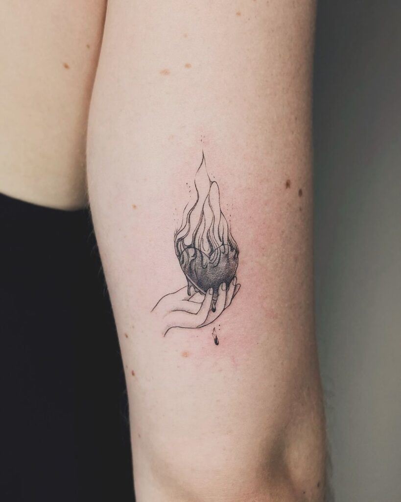 Tatuagem de uma mão a segurar um coração de fogo