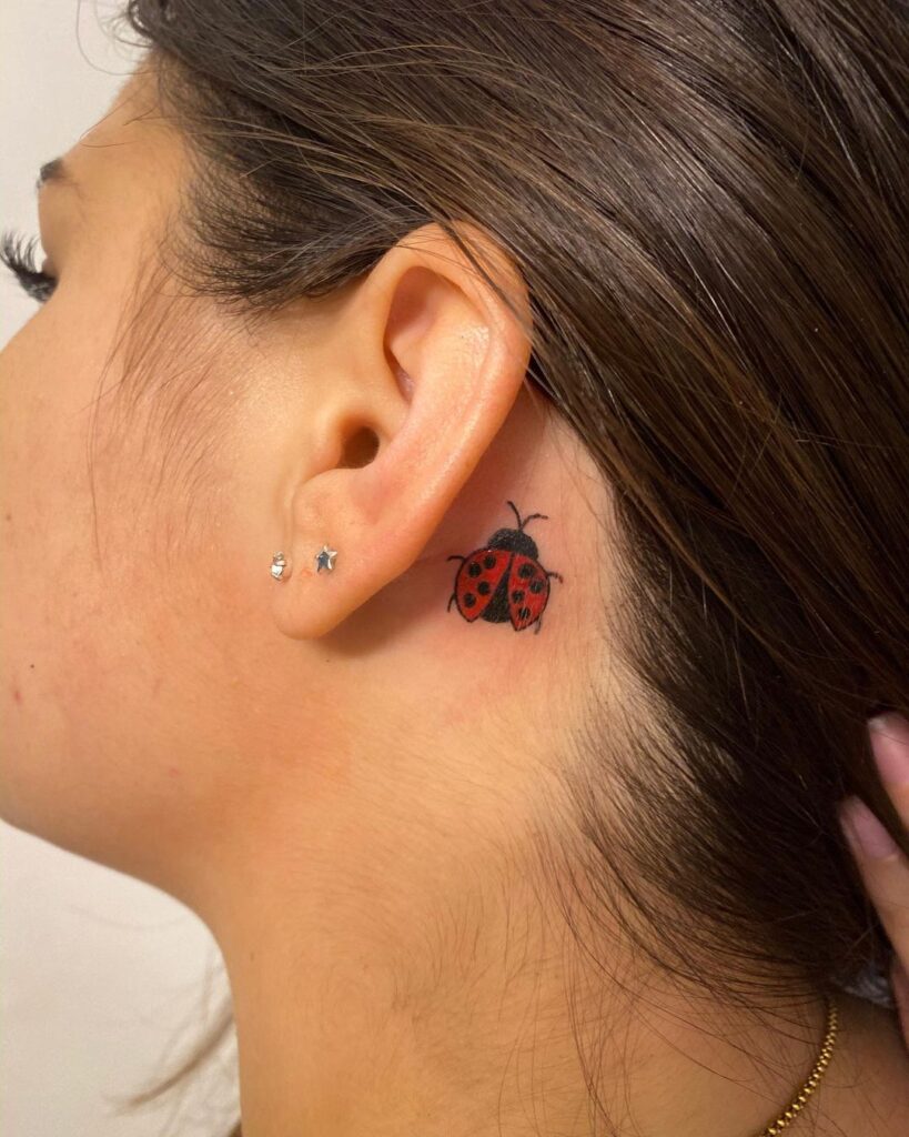 Tatuaggio coccinella dietro l'orecchio