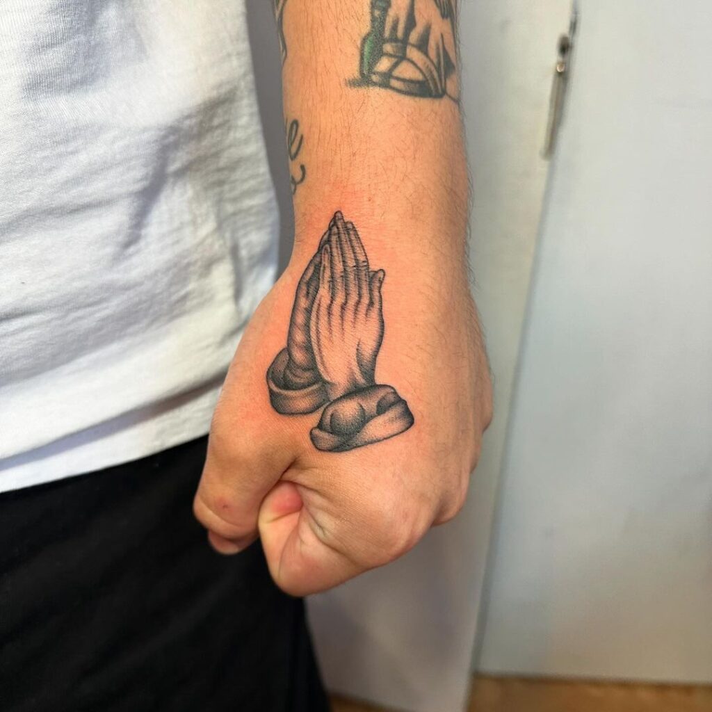 Tatuagem de mãos com mãos a rezar