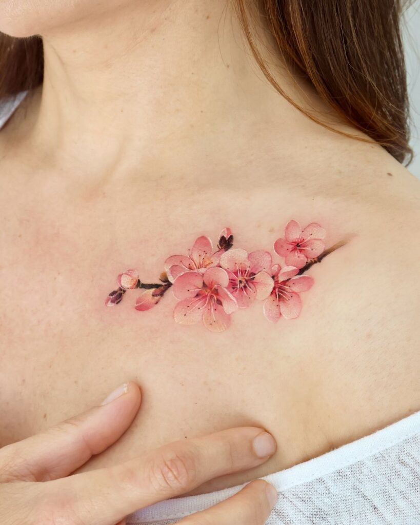 Tatuaje realista de flor de cerezo en la clavícula