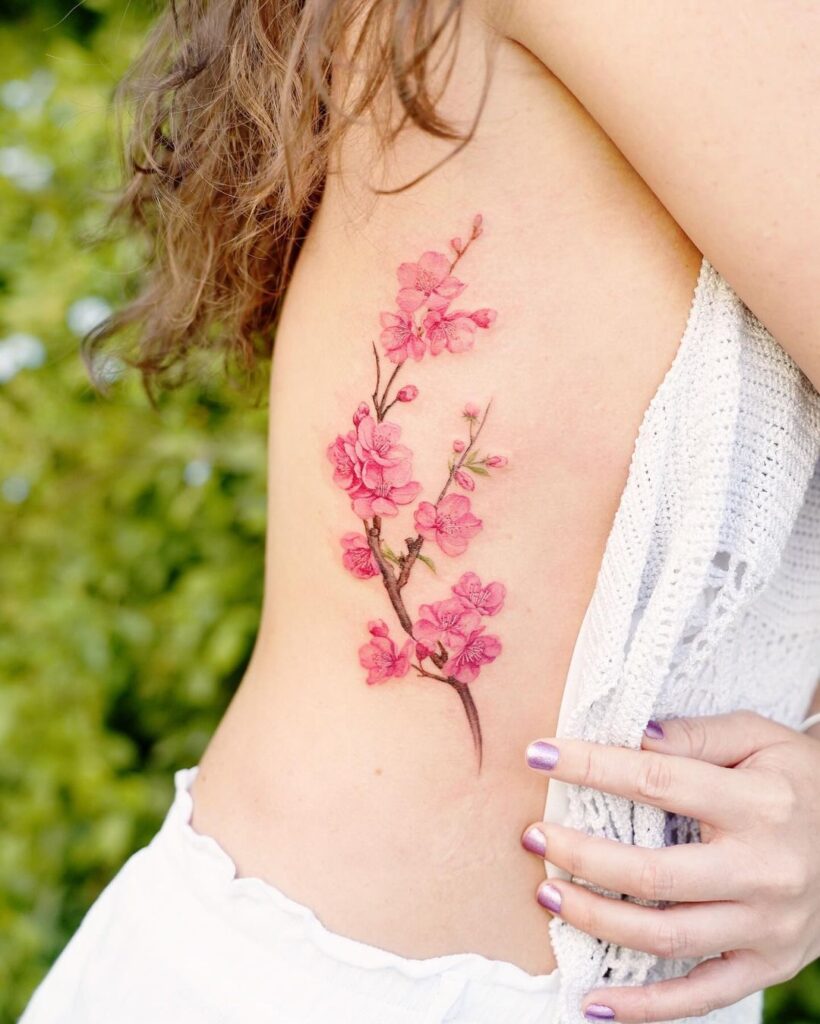 Tatuaggio con fiori di ciliegio sulla gabbia toracica