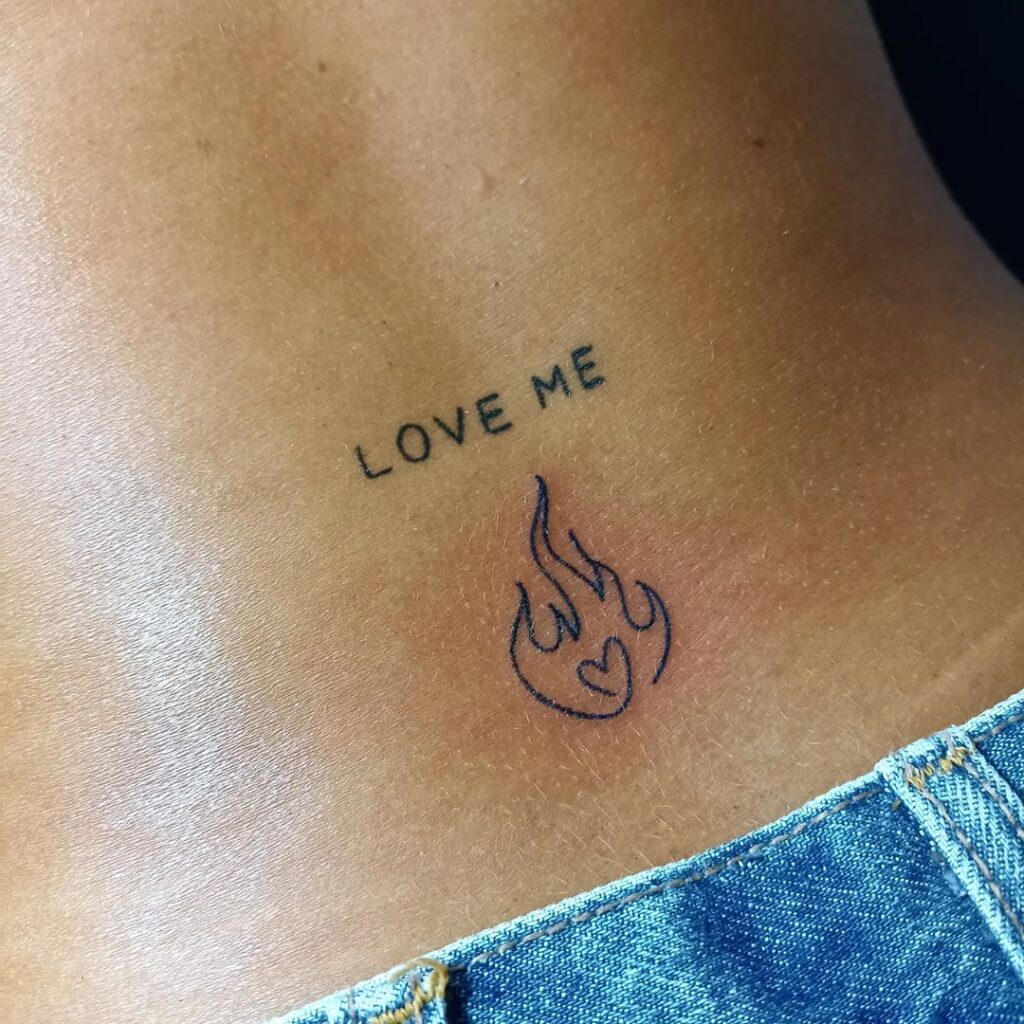 Pequeño tatuaje de corazón de fuego con frase