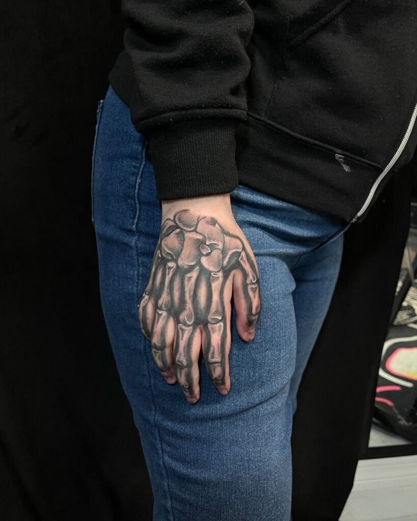 Tatuaje de hueso negro y gris en la mano