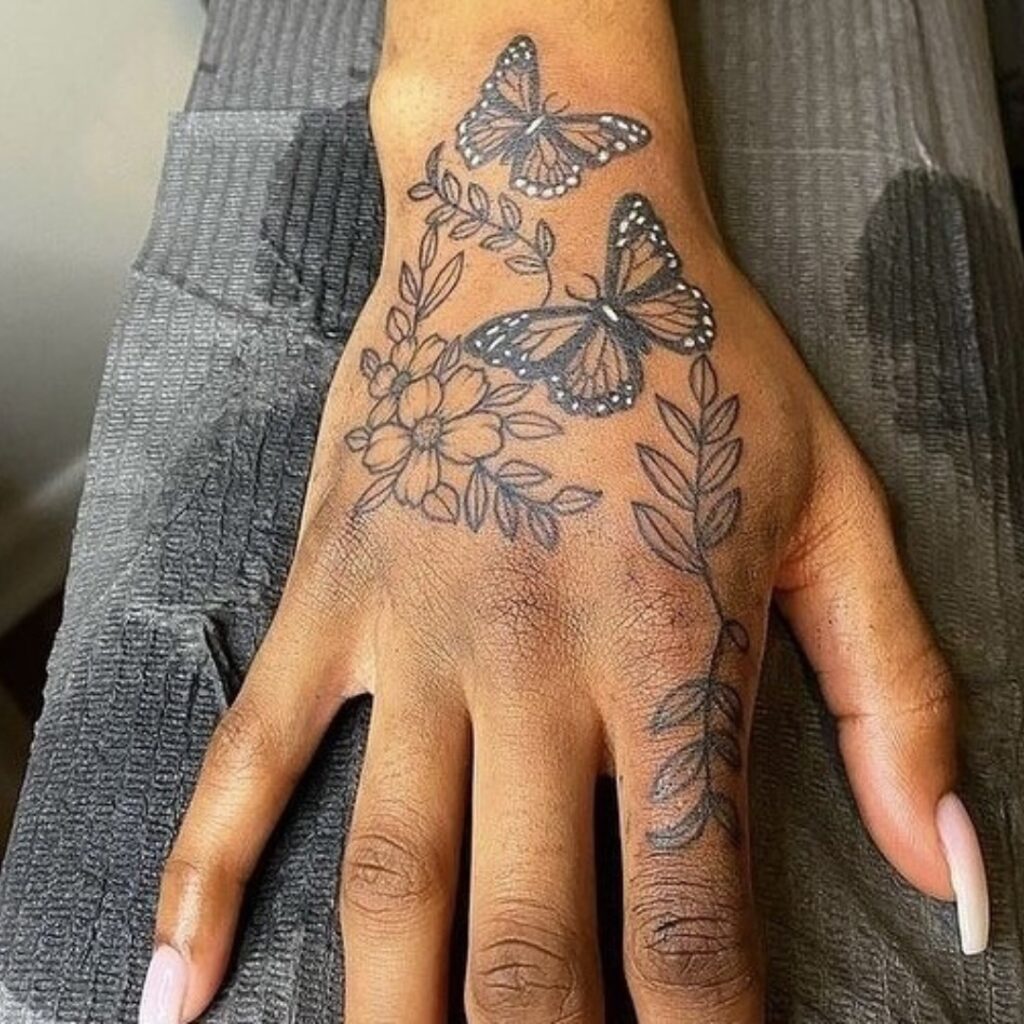 Tatuagem de mão de borboletas e flores