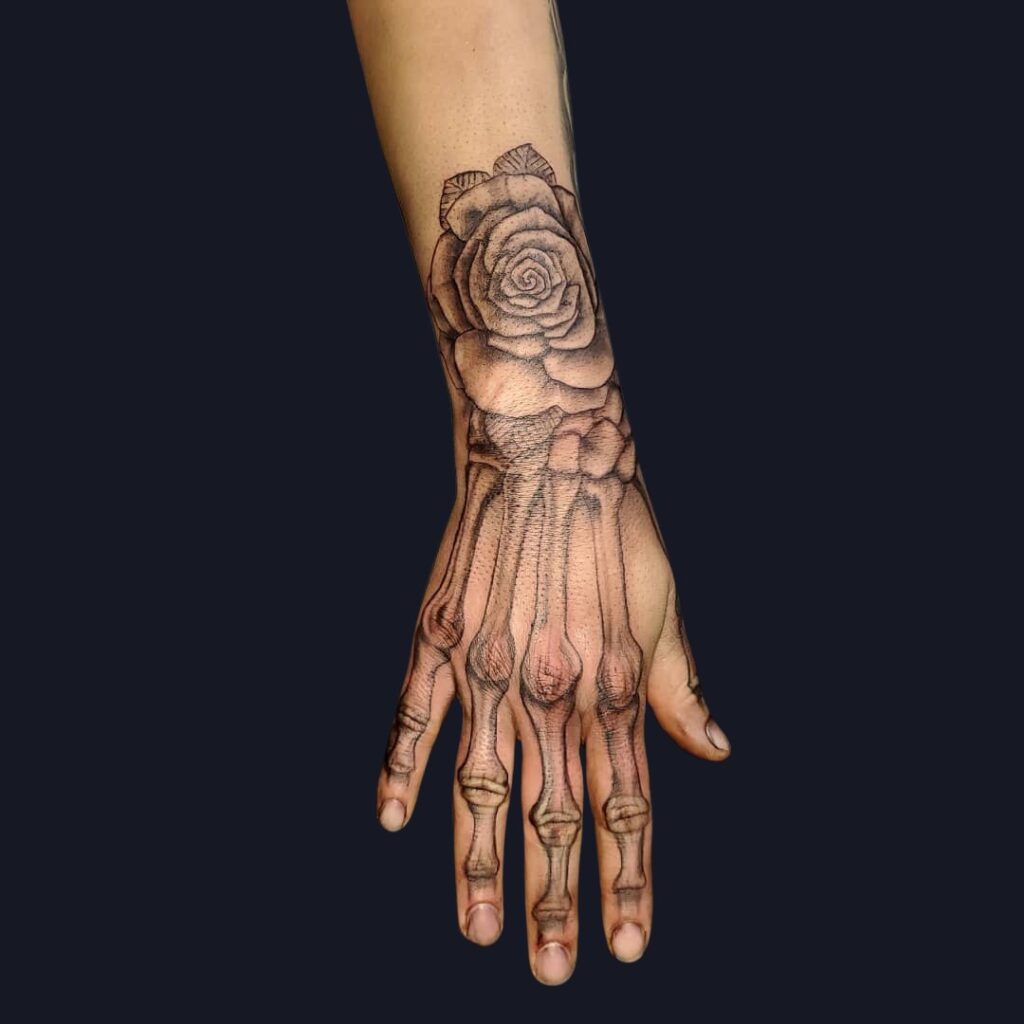 Tatuaje de rosa y hueso en la mano