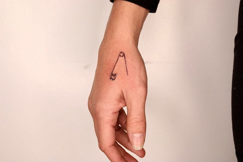 Tatuaje de mano con imperdible pequeño