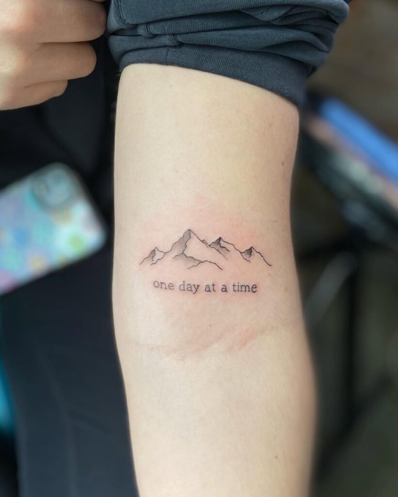 Tatuaggio di montagna con citazione motivazionale